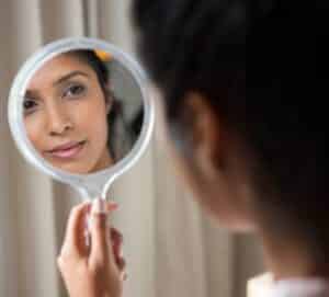 tweakments - woman looking in mirror