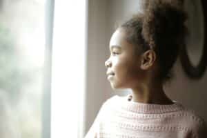 tinea capitis as depicted by a black girl looking out the window