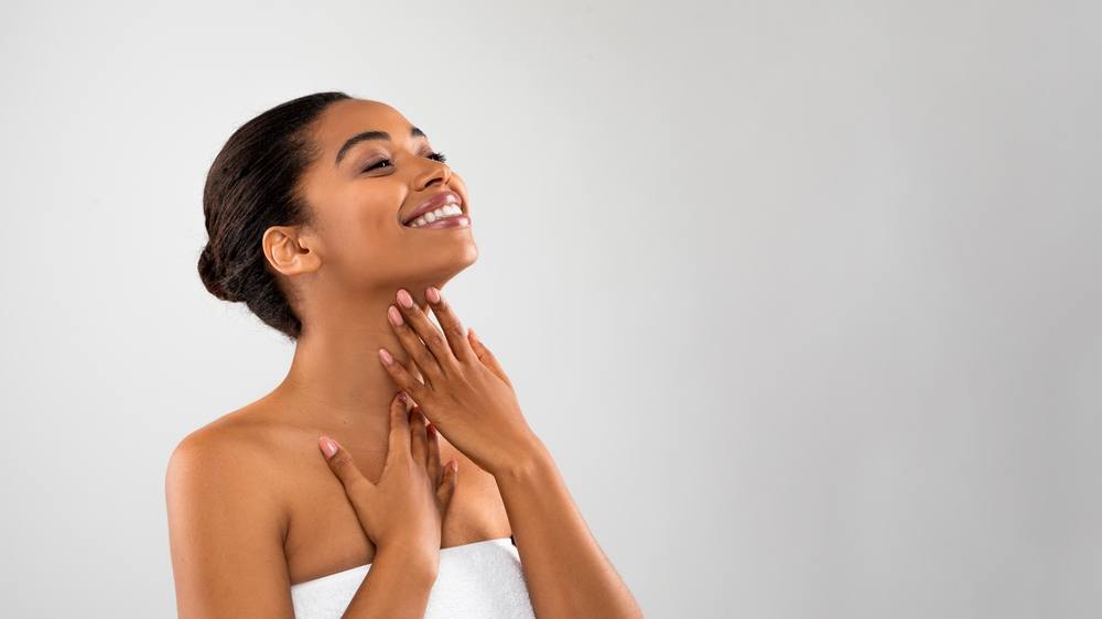 A young woman touching her neck and chin.