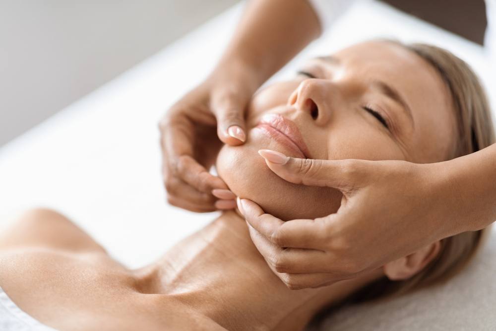 A woman receiving a facial massage at a spa.